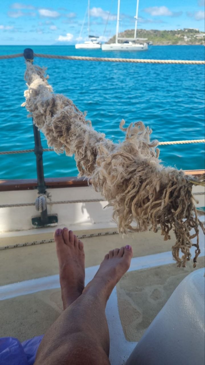 Bare feet and rope on deck above turquoise water
