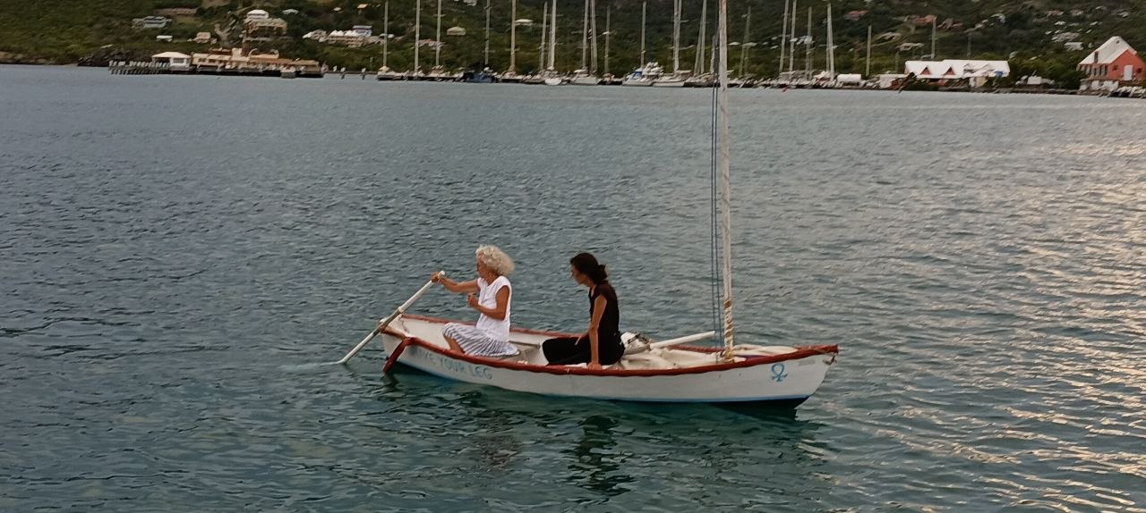 Two women rowing a dinghy in a quiet anchorage